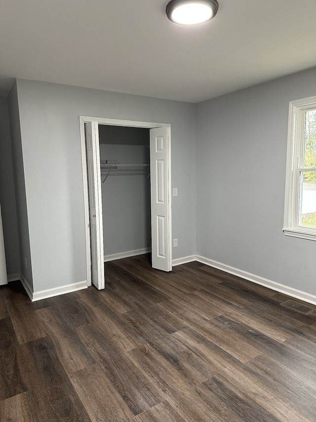 unfurnished bedroom with a closet and dark hardwood / wood-style floors