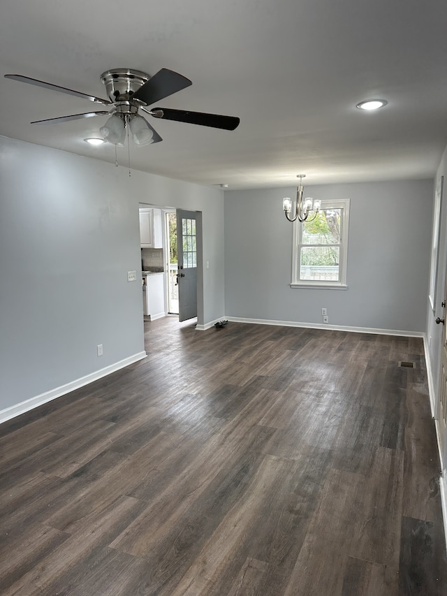 spare room featuring dark hardwood / wood-style floors and ceiling fan with notable chandelier