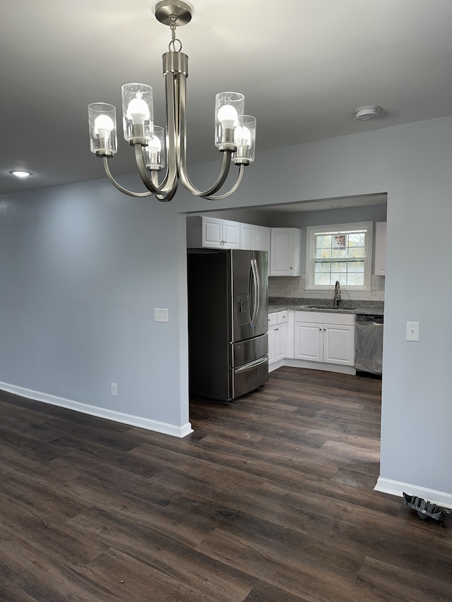 kitchen featuring appliances with stainless steel finishes, white cabinets, decorative backsplash, hanging light fixtures, and a notable chandelier