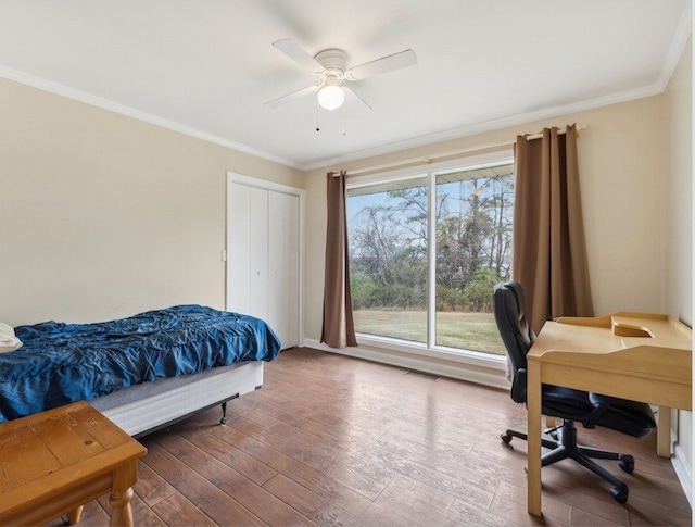 bedroom featuring hardwood / wood-style floors, a closet, ceiling fan, and ornamental molding