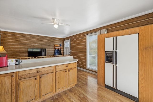 kitchen featuring ceiling fan, wood walls, light wood-type flooring, and white fridge with ice dispenser