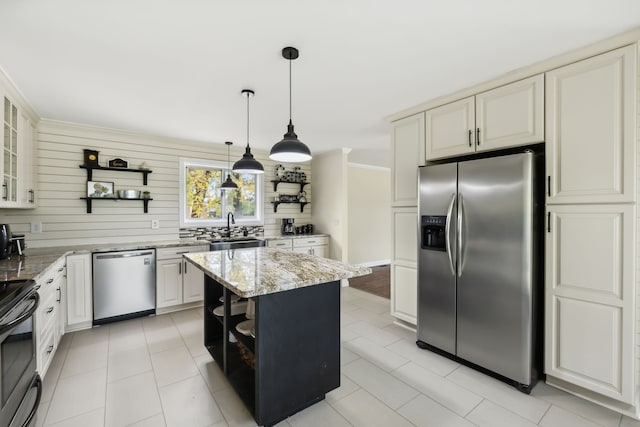 kitchen featuring a center island, sink, tasteful backsplash, light stone counters, and appliances with stainless steel finishes