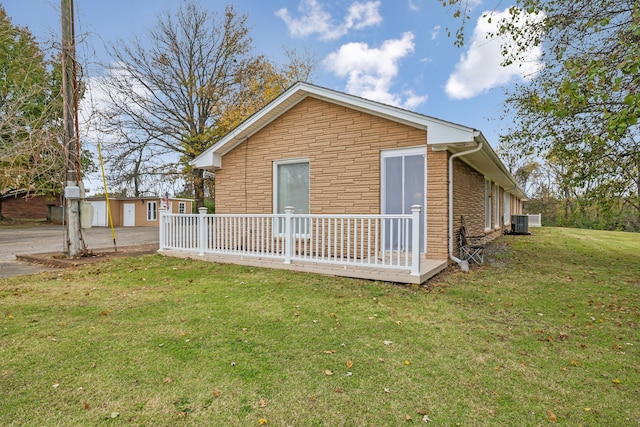 view of side of home with central AC unit, an outbuilding, and a yard