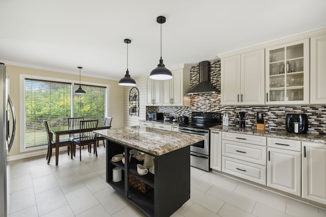 kitchen featuring a center island, wall chimney exhaust hood, decorative backsplash, light stone countertops, and stainless steel appliances