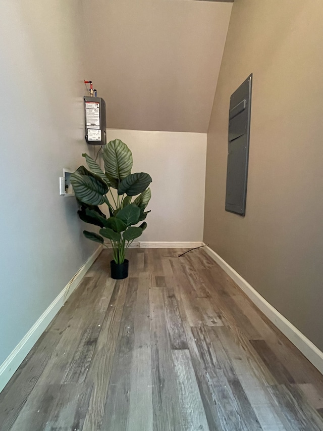 hallway featuring hardwood / wood-style floors, electric panel, and vaulted ceiling