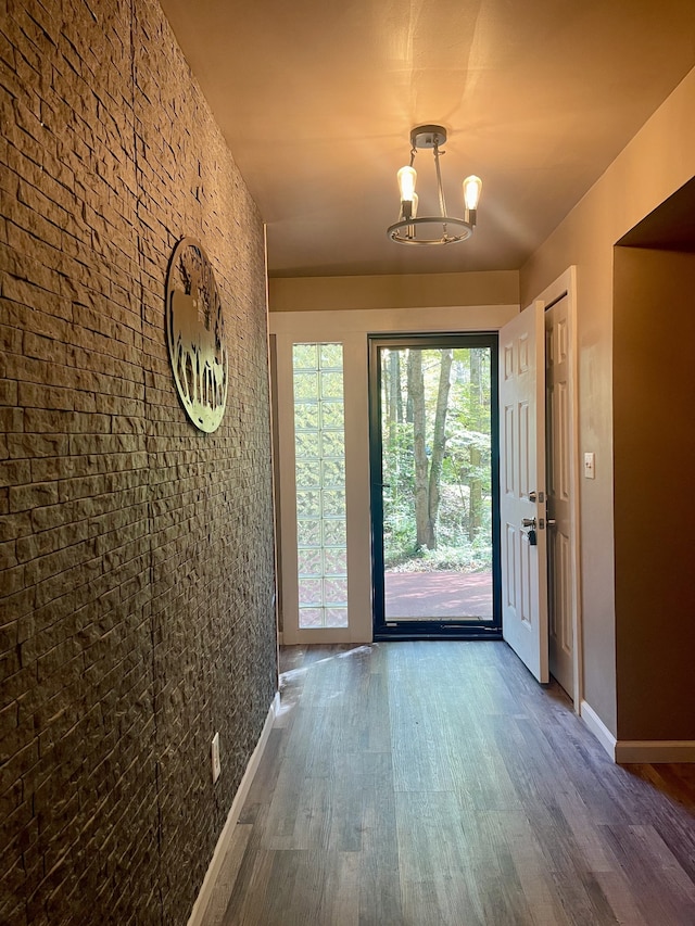 doorway to outside with an inviting chandelier and dark wood-type flooring