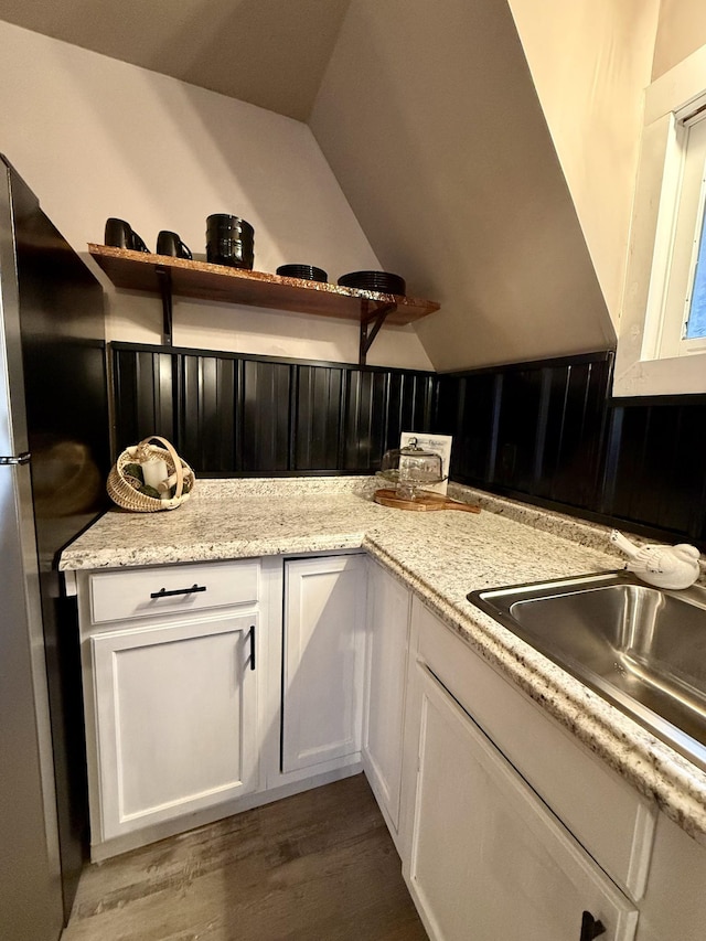 kitchen featuring light stone countertops, stainless steel fridge, dark hardwood / wood-style flooring, sink, and white cabinetry