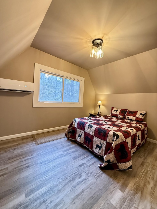 bedroom with wood-type flooring, a wall unit AC, and lofted ceiling