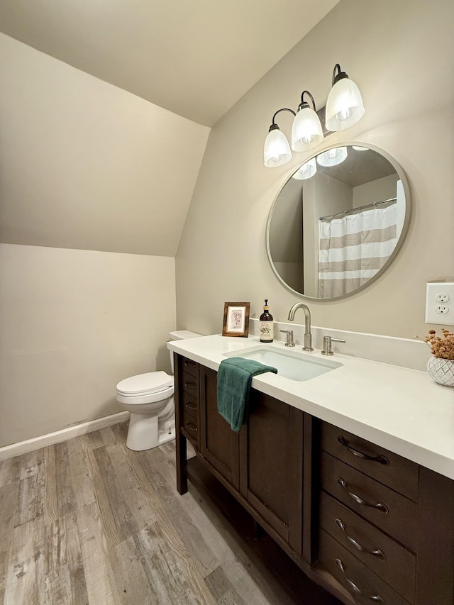 bathroom with vanity, hardwood / wood-style flooring, toilet, and lofted ceiling