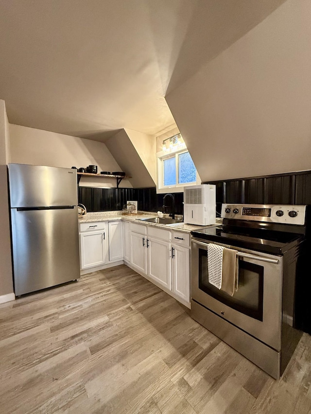 kitchen featuring appliances with stainless steel finishes, light wood-type flooring, white cabinetry, and sink