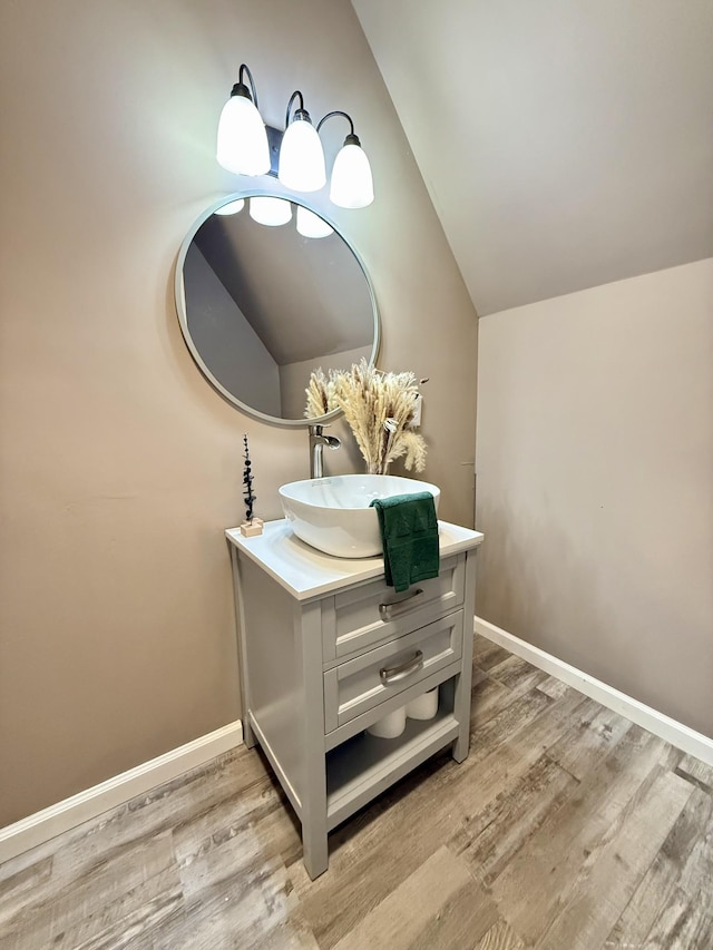 bathroom with vanity, wood-type flooring, and vaulted ceiling