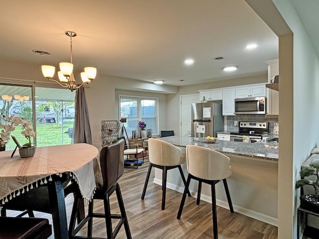 dining room with light wood-type flooring and an inviting chandelier