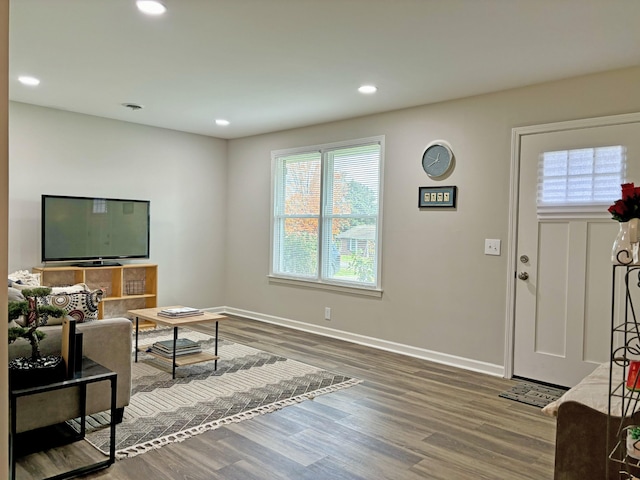 living room with dark wood-type flooring and a healthy amount of sunlight