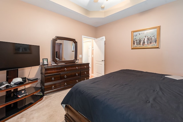 bedroom with light colored carpet, a raised ceiling, and ceiling fan