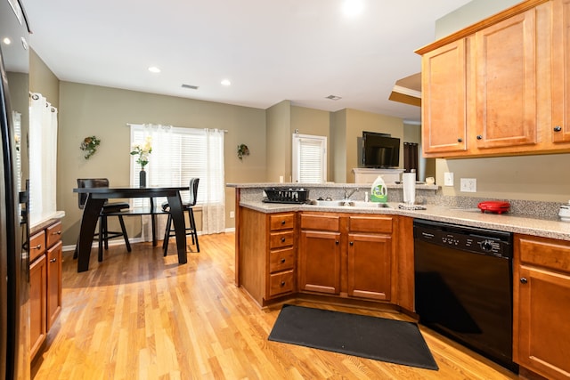 kitchen with kitchen peninsula, sink, light wood-type flooring, and black dishwasher