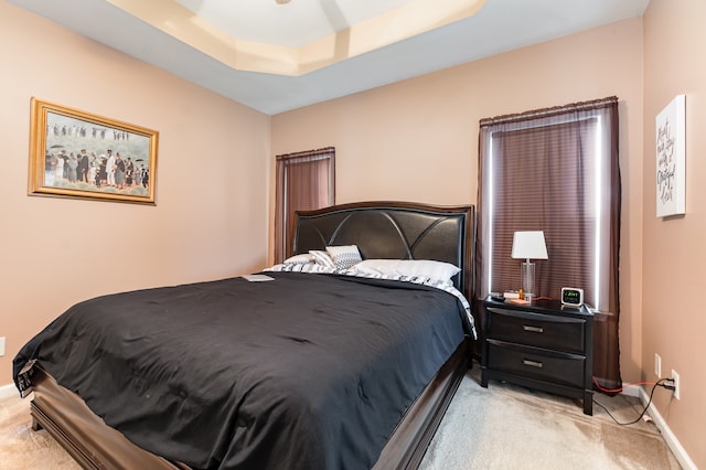 bedroom featuring light carpet and a tray ceiling