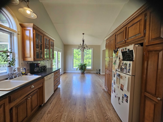 kitchen featuring white appliances, vaulted ceiling, sink, wood-type flooring, and a chandelier