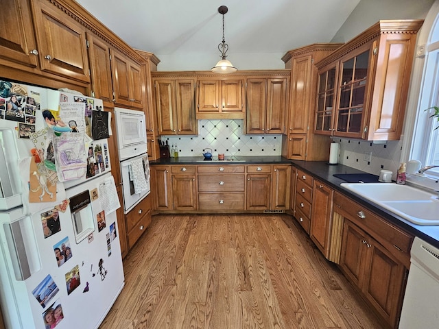 kitchen with decorative backsplash, white appliances, sink, hardwood / wood-style floors, and hanging light fixtures