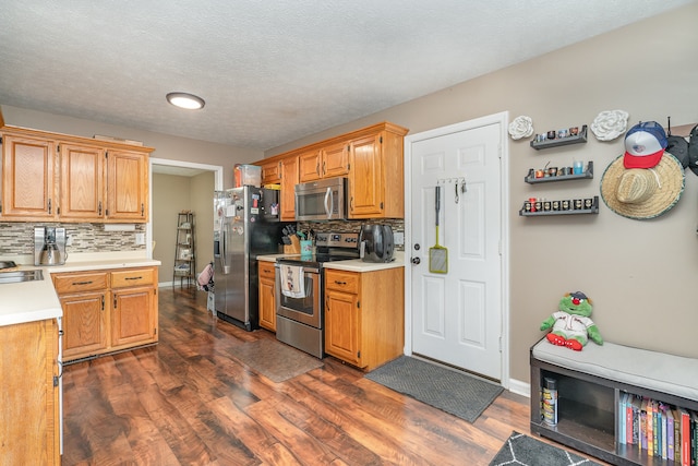 kitchen with a textured ceiling, tasteful backsplash, stainless steel appliances, and dark wood-type flooring