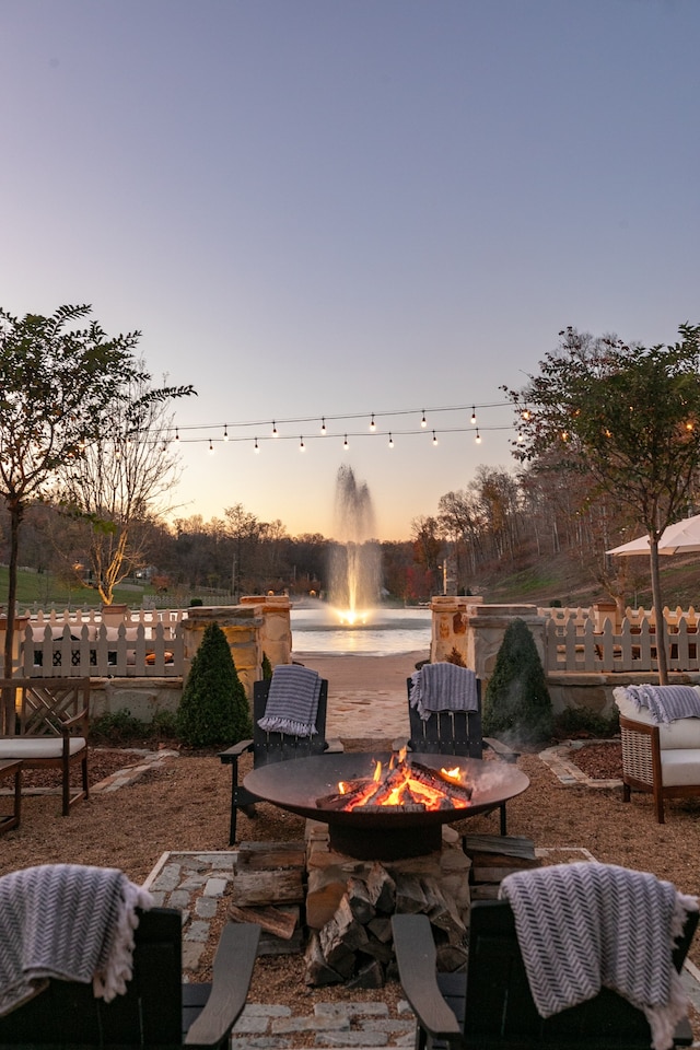 patio terrace at dusk with a water view and an outdoor fire pit