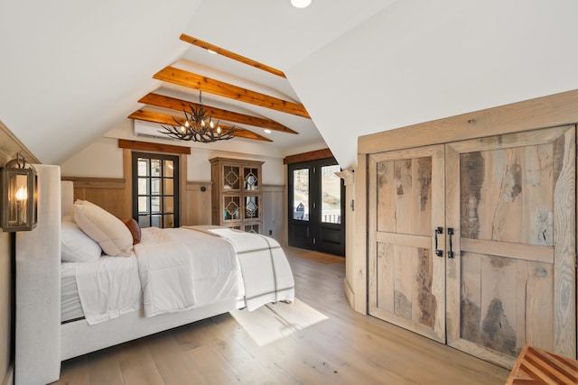 bedroom with french doors, vaulted ceiling with beams, a notable chandelier, light hardwood / wood-style floors, and wooden walls