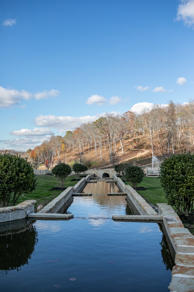 view of swimming pool featuring a water view and a yard