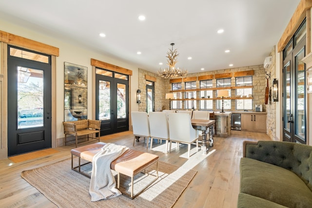 living room with french doors, wine cooler, light hardwood / wood-style flooring, a notable chandelier, and a wall mounted AC