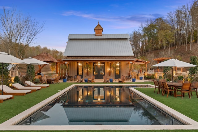 back house at dusk featuring an outdoor structure and a lawn