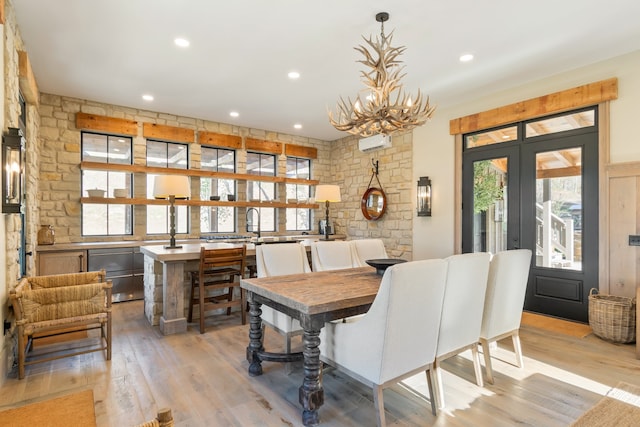 dining space featuring a wall unit AC, a notable chandelier, and light wood-type flooring