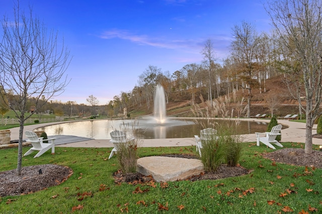 view of property's community with a lawn and a water view