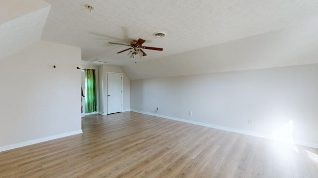 interior space featuring a textured ceiling, ceiling fan, vaulted ceiling, and light wood-type flooring