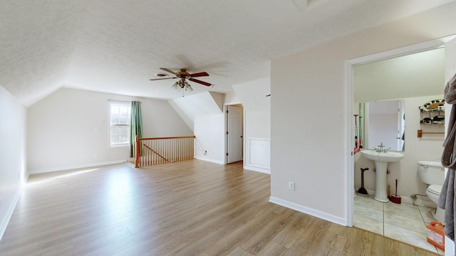 bonus room with ceiling fan, light hardwood / wood-style floors, lofted ceiling, and a textured ceiling