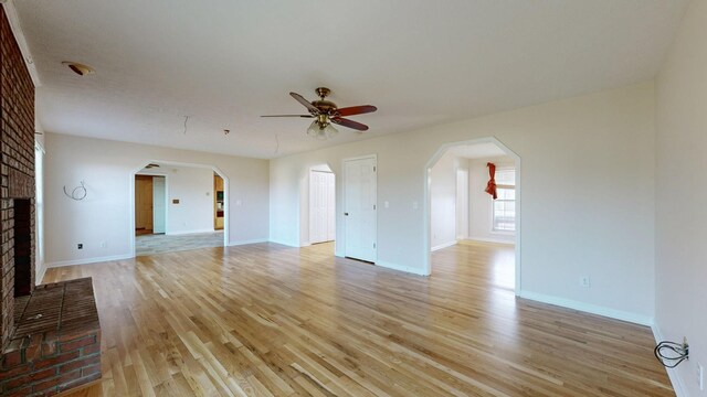 unfurnished living room with a fireplace, light wood-type flooring, and ceiling fan