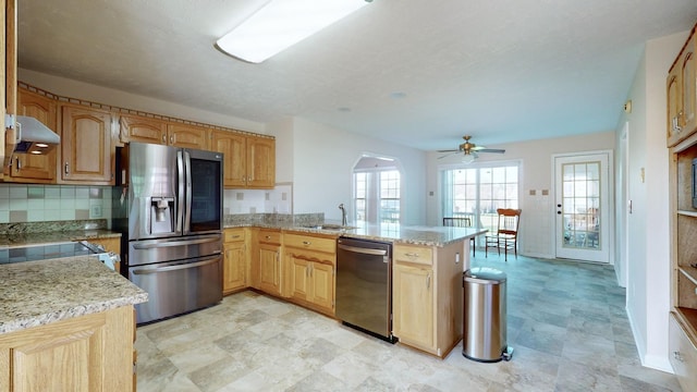 kitchen with ceiling fan, light stone counters, backsplash, kitchen peninsula, and appliances with stainless steel finishes