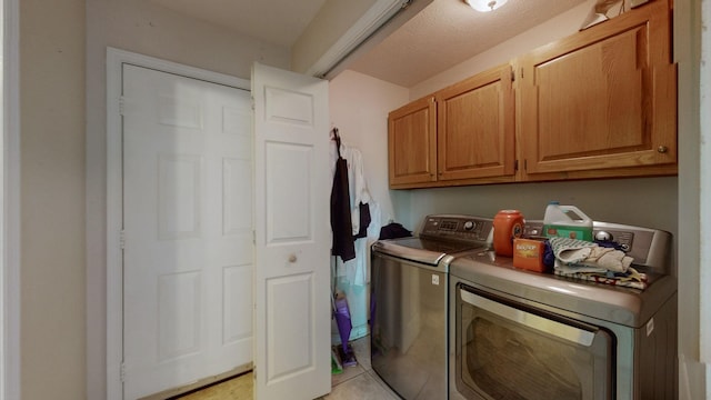 laundry room with cabinets, independent washer and dryer, a textured ceiling, and light tile patterned floors