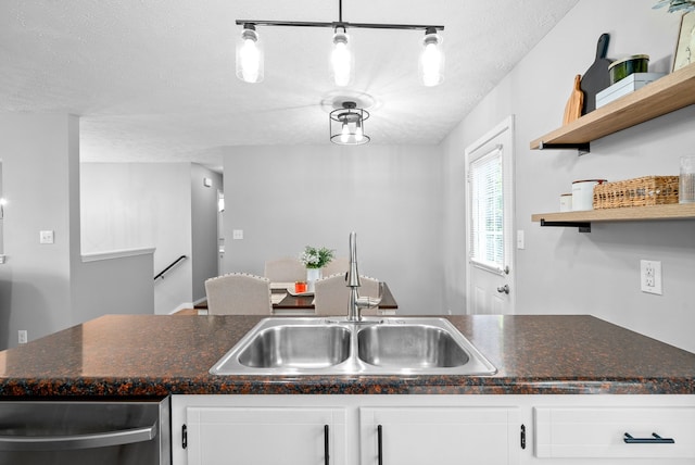 kitchen featuring white cabinets, rail lighting, sink, and a textured ceiling