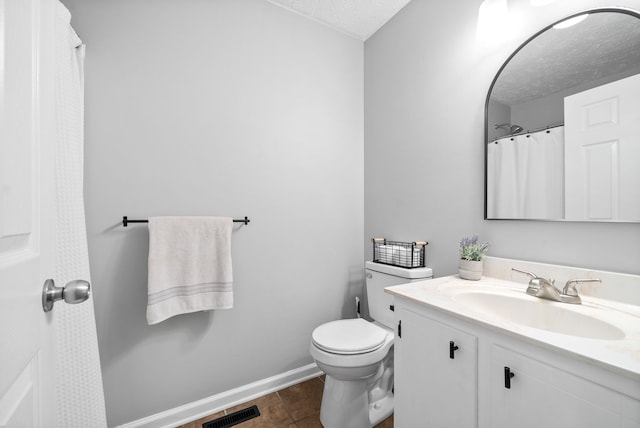 bathroom with tile patterned flooring, a textured ceiling, vanity, and toilet