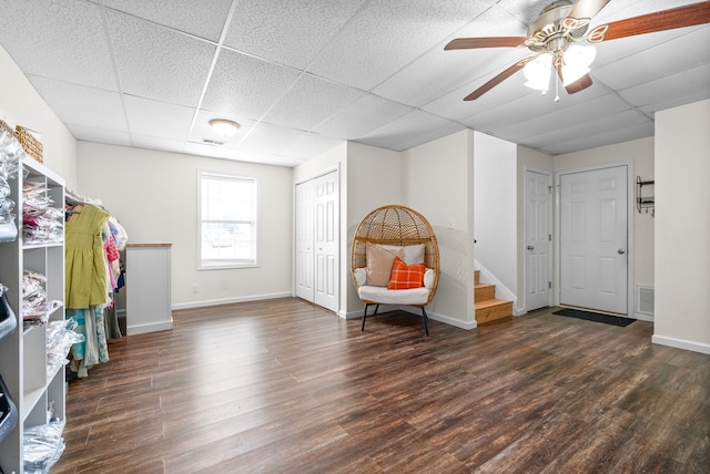 interior space featuring dark hardwood / wood-style flooring, a drop ceiling, and ceiling fan