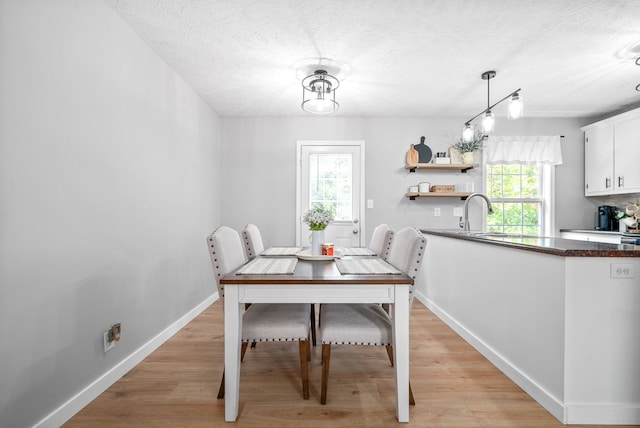 dining area featuring a textured ceiling, sink, and light hardwood / wood-style flooring