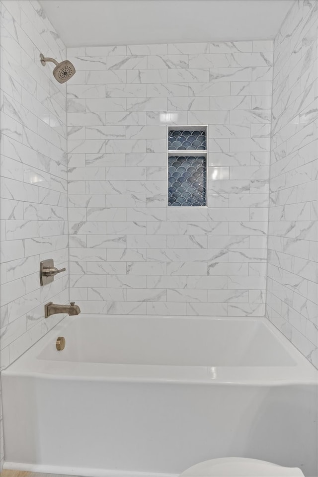 bathroom with toilet and tiled shower / bath