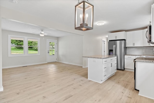 kitchen featuring light hardwood / wood-style flooring, ceiling fan, appliances with stainless steel finishes, a kitchen island, and white cabinetry