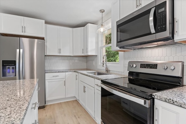 kitchen with white cabinets, sink, decorative backsplash, decorative light fixtures, and stainless steel appliances