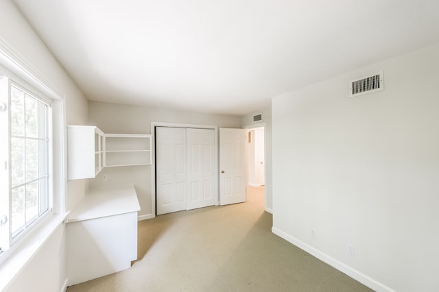 unfurnished bedroom featuring light colored carpet, a closet, visible vents, and baseboards