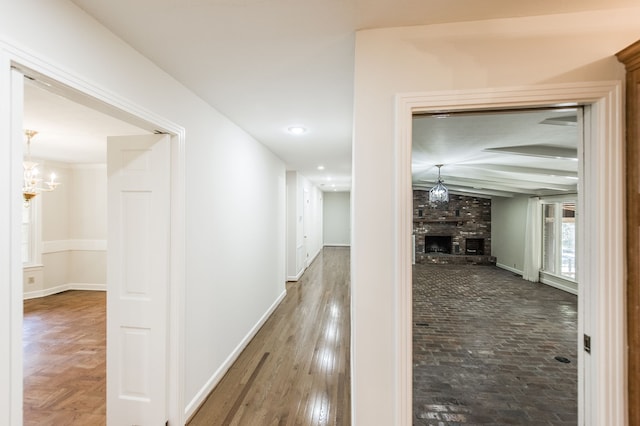 corridor featuring a notable chandelier, baseboards, and wood finished floors