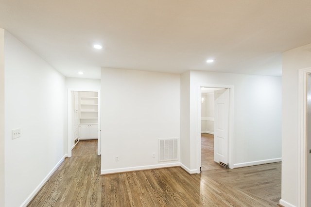 spare room with recessed lighting, visible vents, baseboards, and wood finished floors