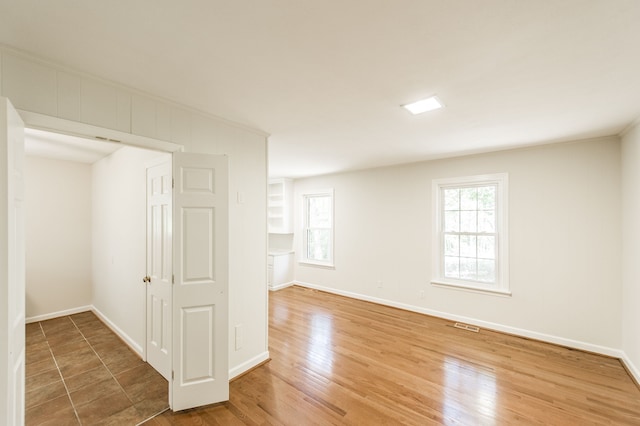 empty room with visible vents, baseboards, and wood finished floors