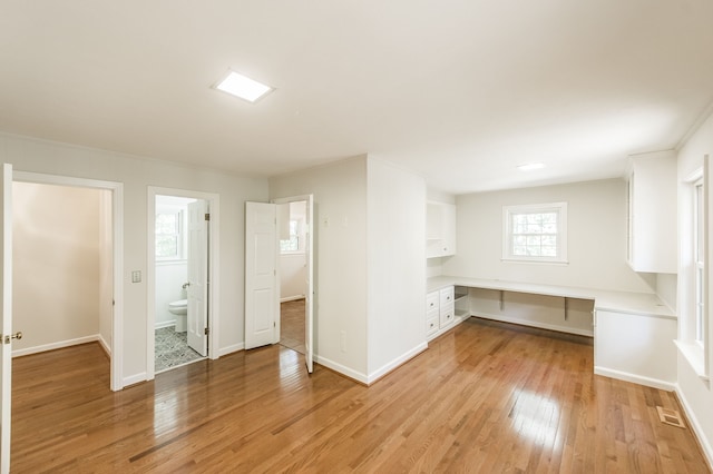 interior space featuring visible vents, built in study area, light wood-style flooring, and baseboards