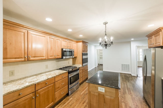 kitchen featuring appliances with stainless steel finishes, dark stone counters, visible vents, and tasteful backsplash