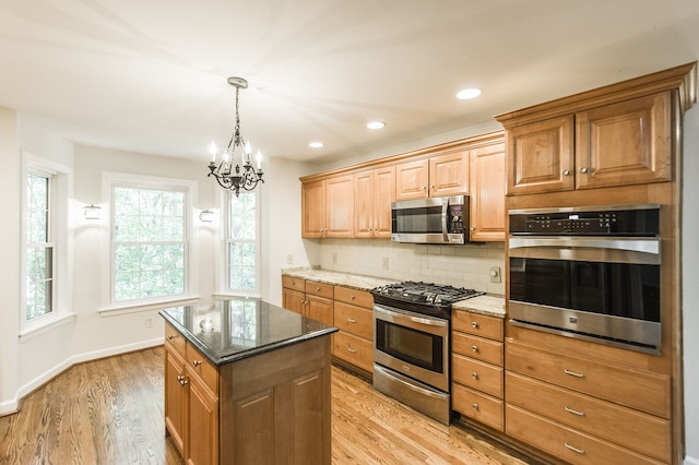 kitchen featuring appliances with stainless steel finishes, dark stone counters, a kitchen island, and decorative backsplash