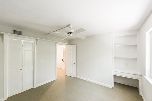 unfurnished bedroom with a ceiling fan, baseboards, visible vents, and built in desk